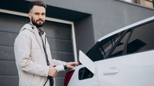 Wszystkie wiadomości - mezczyzna ladujacy samochod elektryczny przy domu 1