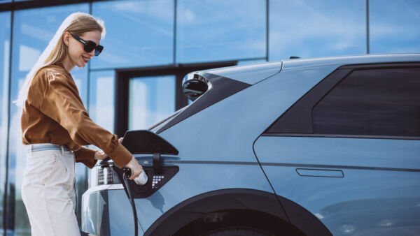 Strefa Wiedzy - woman puts charging cable into electric car