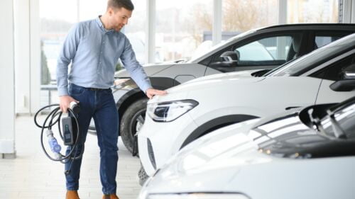 Wszystkie wiadomości - concept buying electric vehicle handsome business man stands near electric car dealership