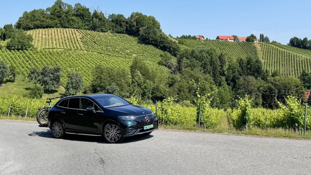 Samochód elektryczny Mercedes EQE SUV z bagażnikiem rowerowym na tle winorośli w Styrii (Austria)