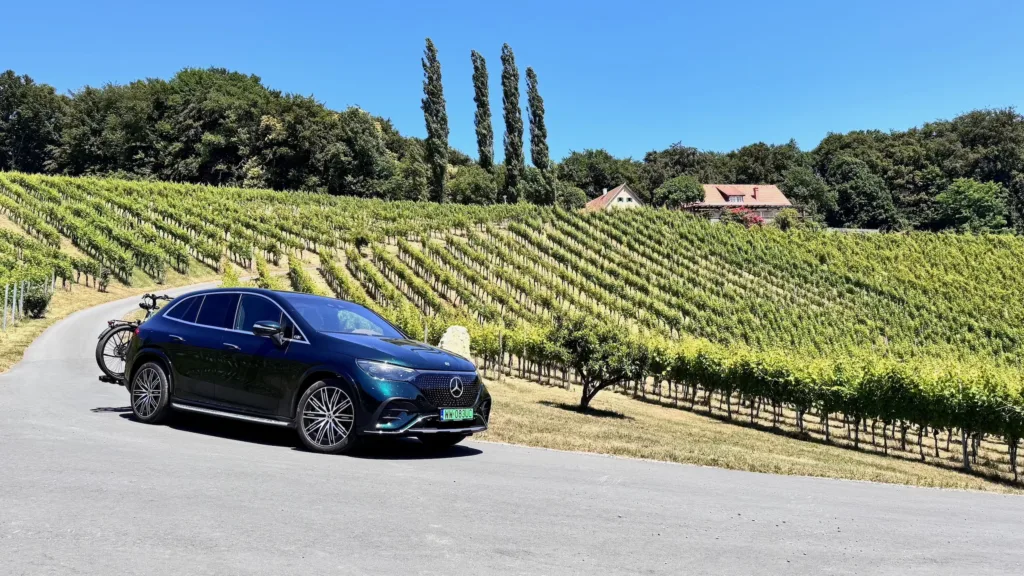 Samochód elektryczny Mercedes EQE SUV z bagażnikiem rowerowym na tle winnicy w Styrii
