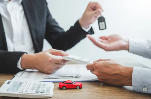 Sale agent giving Car key to customer and sign agreement contract, Insurance car concept.