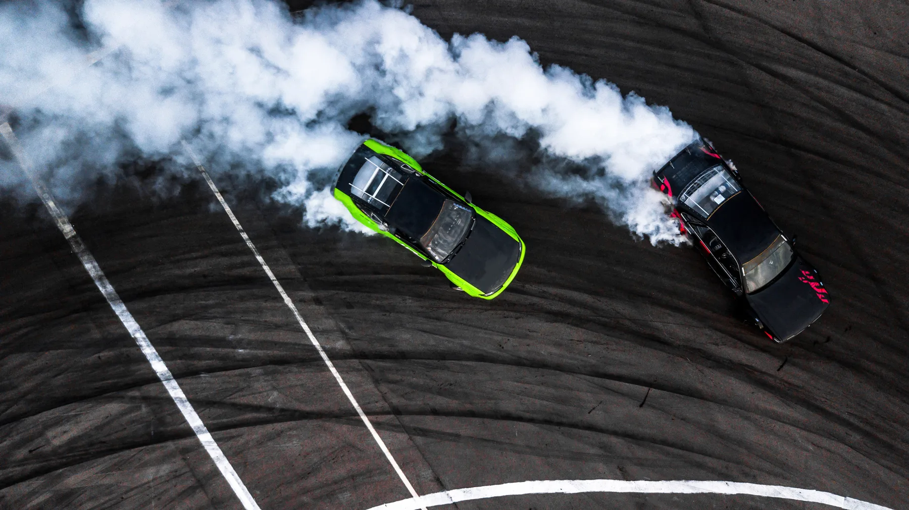 Car drift battle, Two car drifting battle on race track with smoke, Aerial view.